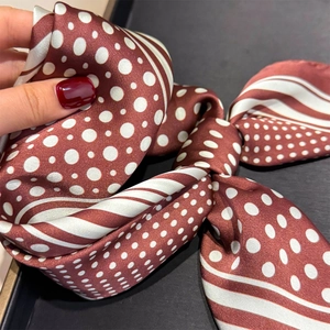 Gros plan détaillé du foulard en soie bordeaux et blanc à pois avec texture géométrique