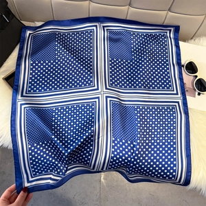 Détail d'un foulard en soie à pois bleu et blanc avec bordure géométrique sur tapis