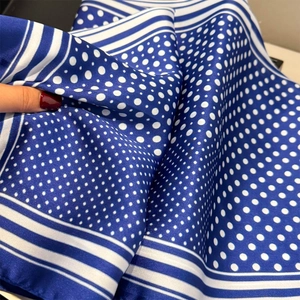 Vue détaillée du motif à pois et de la texture satinée sur un foulard en soie bleu