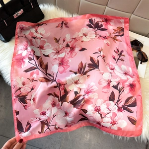 Detailed view of pink floral silk scarf with cherry blossom print on faux fur surface