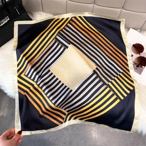 Elegant geometric stripe silk-like square scarf in navy and yellow draped on soft fur