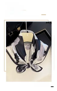 Close-up of luxury floral silk scarf tied elegantly on a black leather handbag