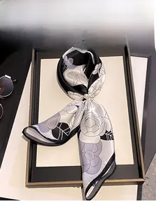 Detailed view of camellia print mulberry silk scarf with a gold pearl buckle accessory