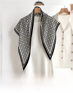 Dettaglio di un foulard di seta bianco e nero con bordi a strisce su una gruccia
