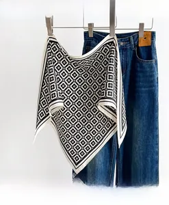 Dettaglio di un foulard in seta bianco e nero con motivo geometrico e denim casual