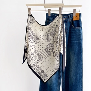 Vintage Seidenschal mit Paisleymuster und gewaschene Denim-Jeans vor weißem Hintergrund