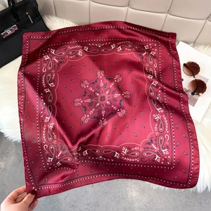 Detail of burgundy paisley silk scarf with mandala patterns on a plush white rug background