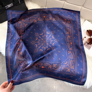 Detailed view of luxury paisley print silk scarf in navy blue and orange with fine stitching