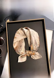 Macro detail of paisley mulberry silk scarf with 100% silk certification on elegant tray