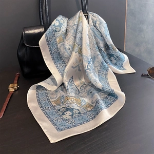 Blue and white paisley 100% silk square scarf draped over a black handbag