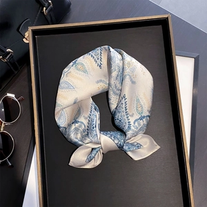 Detail of silk scarf with blue paisley pattern styled on a black display tray
