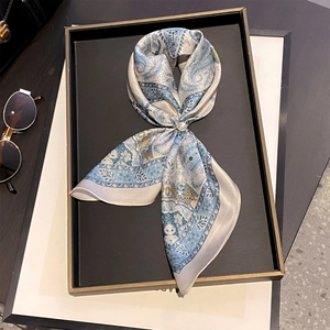 Detail of light blue paisley silk scarf with a pearl ring buckle on a display tray