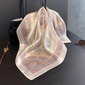 Detail of silk paisley scarf draped on a leather bag with vintage watch and sunglasses