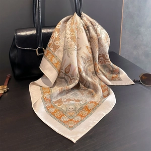 Silk neck scarf with cashew flower paisley print tied on a luxury leather handbag