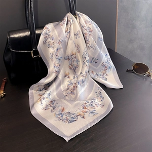 Détail d'un foulard en soie imprimé papillon drapé sur l'anse d'un sac à main