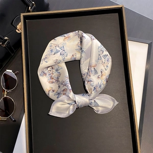 Gros plan d'un foulard en soie avec imprimé papillon bleu clair sur un plateau noir