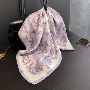 Foulard en soie avec imprimé papillon violet attaché sur un sac à main en cuir noir