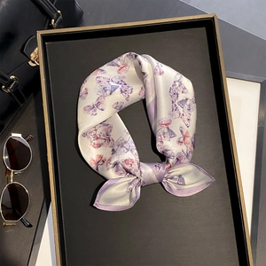 Détail du foulard carré en soie avec imprimé papillon violet sur une surface satinée