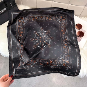 Vintage paisley print square silk scarf with black and orange patterns on fur rug