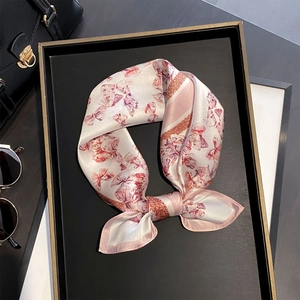 Foulard élégant en soie à imprimé papillons roses exposé sur un plateau avec accessoires