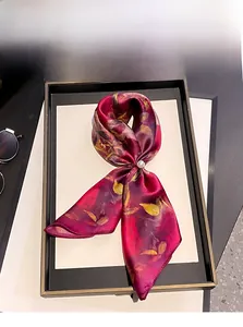 Vue détaillée du foulard en soie rouge avec motif floral jaune et boucle perle