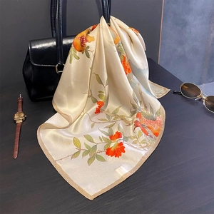 Eleganter Seidenschal mit Granatapfelmuster über Handtasche drapiert mit Satinglanz
