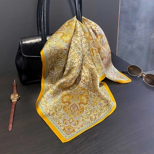 Seidenquadrat mit Paisley-Muster in Gelb und Gold auf einer schwarzen Ledertasche