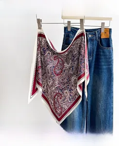 Detail view of paisley print silk scarf with red and blue pattern hanging on jeans