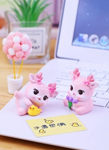 Nahaufnahme von rosa Hirschfiguren mit Enten- und Tulpendekor auf einem Schreibtisch