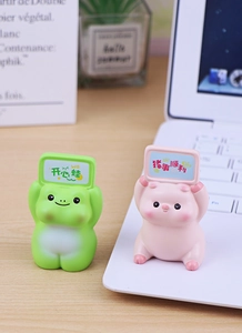 Cute resin frog and pig desktop figurines holding signs on a wooden office desk