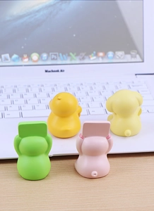 Macro view of four colorful animal phone holders on a wooden desk near a laptop