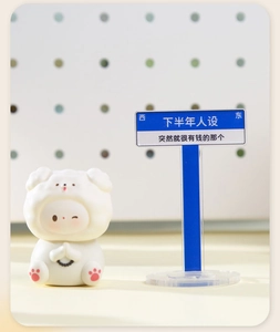 Close-up of cute white baby resin figure in bear outfit holding prayer beads for desk