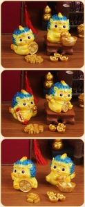 Detailed view of three yellow Pi Xiu figurines holding gold ingots for wealth and good luck