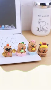 Makroaufnahme von vier süßen Capybara-Harzfiguren auf einem Schreibtisch am Laptop