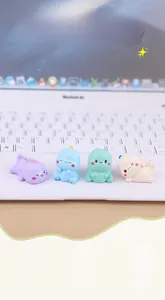 Close-up of four colorful mini resin dinosaur figurines on a white laptop keyboard