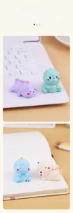 Mini dinosaur ornaments in pastel colors placed on a desk next to a laptop for decoration