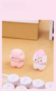 Close-up of pink pig and white unicorn flocked miniature figures on a warm wooden desk