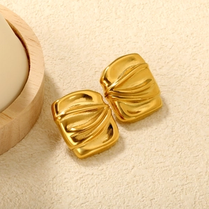 Detail of square gold earrings featuring irregular crumpled texture and metallic luster