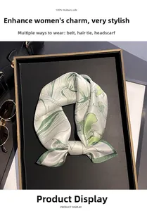 Close-up of 100% mulberry silk scarf with green botanical prints in a black gift box