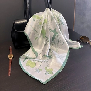 Fresh green floral print 100% mulberry silk scarf tied to a black leather handbag