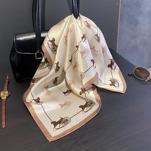 Elegant mulberry silk scarf with classic horse carriage print draped over a black leather handbag