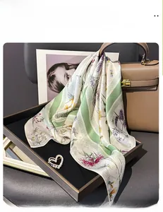 Détail d'un foulard en soie imprimé avec motifs floraux et broche perle en cœur