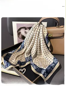 Silk scarf with navy dots and paisley border draped on a brown handbag handle