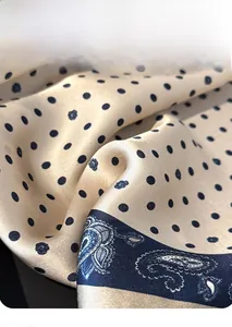 Detail of silk scarf showing navy polka dots and paisley patterns with glossy drape