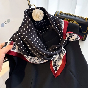 Close-up of a 100% silk scarf with paisley and polka dot print on a camellia hanger