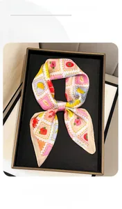 Detail of silk-feel scarf with colorful fruit stamp prints tied in a bow on a display tray