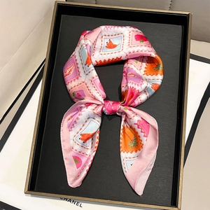 Elegant pink silk scarf with tropical fruit stamp print tied in a bow on a display tray
