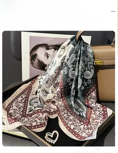 Detail of paisley print silk scarf in green and burgundy tied on a leather handbag