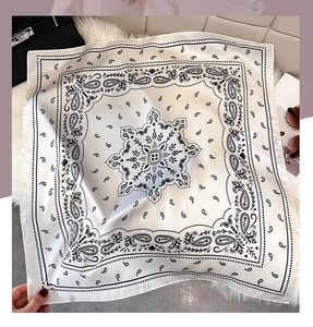 Detail of white paisley faux silk scarf showing fluid drape on plush background