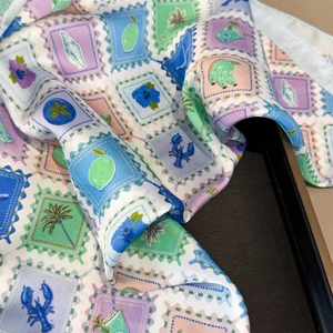 Close-up of tropical stamp print scarf showing smooth silk texture and vibrant summer patterns